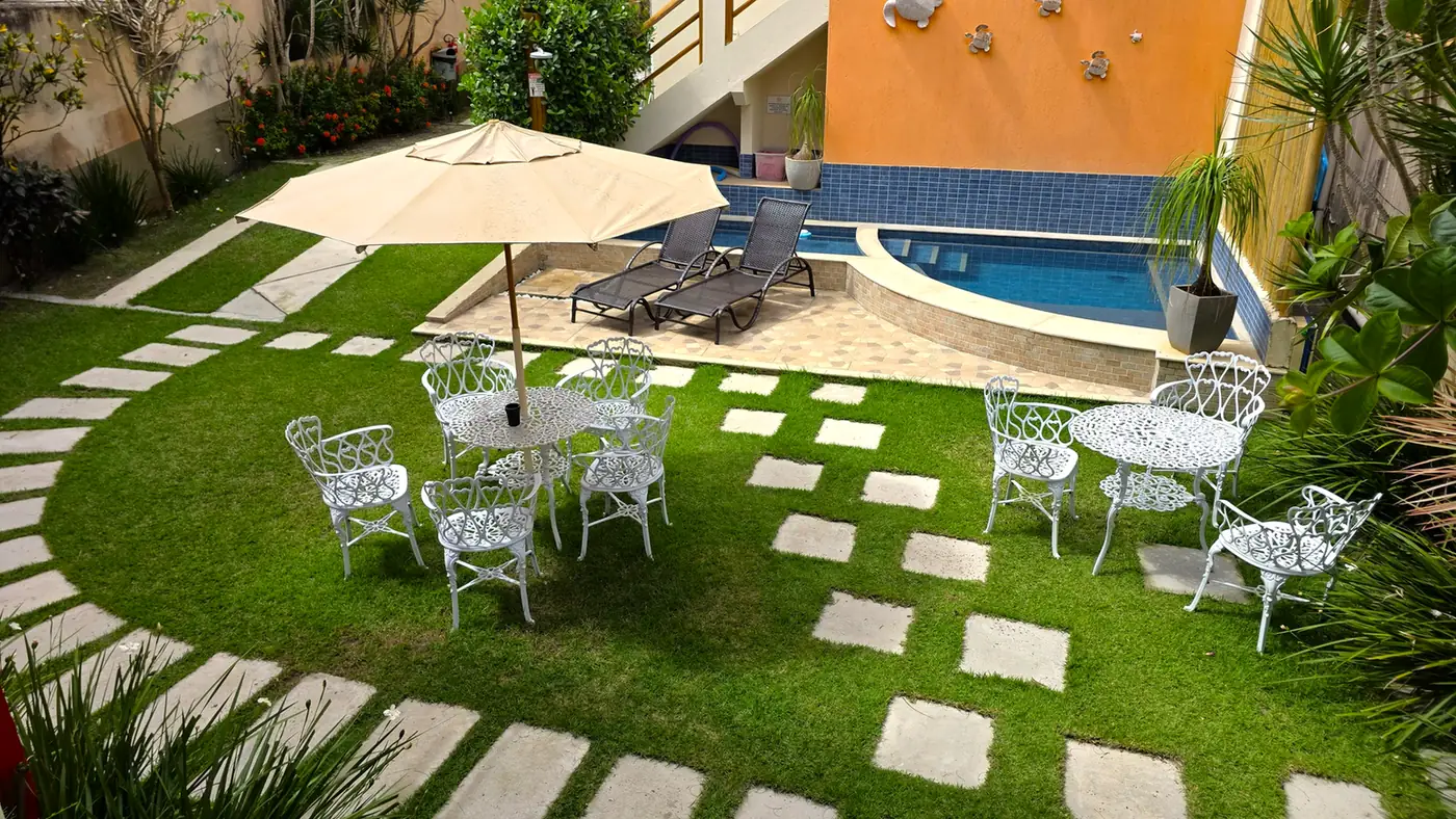 Piscina e jardim com mesas e espreguiçadeiras no Cores do Verão